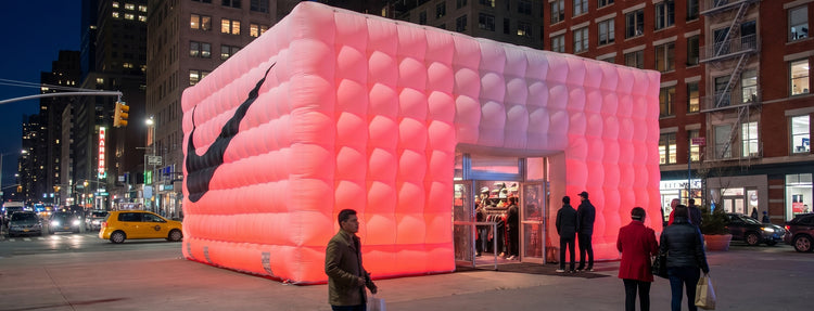 Giant illuminated pink inflatable pop-up retail booth on a city street at night